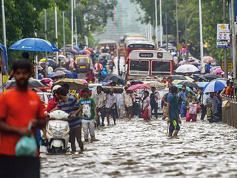 Vehicles and pedestrians wade through a flooded street following heavy monsoon showers in Mumbai.