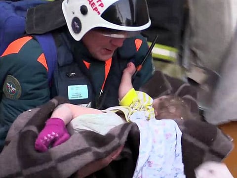 a rescuer carrying a 11-month-old child said to have been found alive, after a gas explosion rocked a residential building in Russia's Urals city of Magnitogorsk