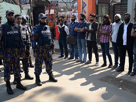 Bangladeshi police stand guard next to left-wing activists wearing black cloth over their mouths at a protest against the allegedly fraudulent victory of the ruling Awami League in the recent general eletion, in Dhaka.