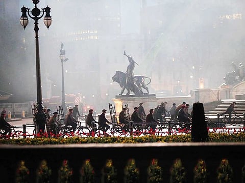 Extras riding bicycles take part in filming of a scene in front of Buckingham Palace.
