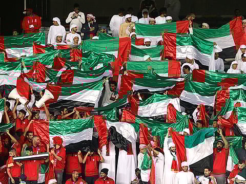 UAE supporters hold up their national flag as they watch the 2019 AFC Asian Cup Group A football match against India at Zayed Sports City stadium in Abu Dhabi  on January 10, 2019. 