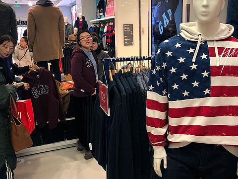 A woman tries out a sweater at a U.S. retailer GAP’s flagship store in Beijing, Thursday, Jan. 10, 2019. Uncertainty over the outcome of China-U.S. trade talks is casting a pall over Asian markets as both sides kept quiet about what lies ahead.