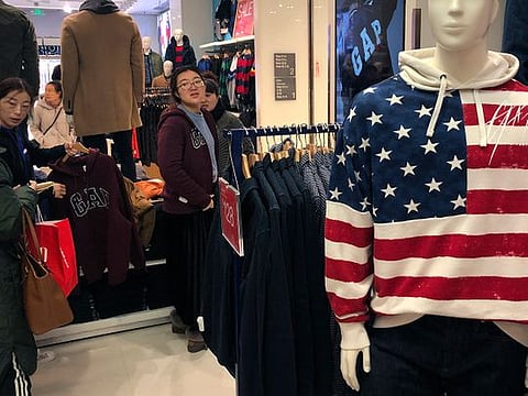 A woman tries out a sweater at a U.S. retailer GAP’s flagship store in Beijing, Thursday, Jan. 10, 2019. Uncertainty over the outcome of China-U.S. trade talks is casting a pall over Asian markets as both sides kept quiet about what lies ahead.