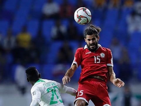 Lebanon's midfielder Haytham Faour, right, jumps to head the ball against Saudi Arabia's midfielder Abdulaziz Al-Bishi, left, during the AFC Asian Cup group E soccer match between Lebanon and Saudi Arabia at Al Maktoum Stadium in Dubai.