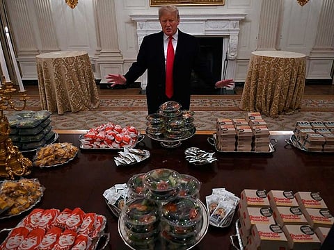President Donald Trump talks to the media about the table full of fast food in the State Dining Room of the White House in Washington, Monday, Jan. 14, 2019, for the reception for the Clemson Tigers.