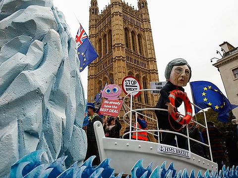 A campaigner for a second Brexit referendum wears a mask depicting U.K. Prime Minister Theresa May while standing on a mock ship as it passes pro and anti-Brexit demonstrations outside Houses of Parliament in London on Tuesday.