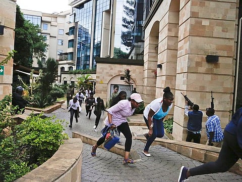 Civilians flee as security forces aim their weapons at a hotel complex in Nairobi, Kenya Tuesday, Jan. 15, 2019.