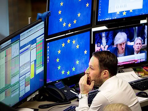 A computer screen shows news about the Brexit with Prime Minister Theresa May as a broker watches his screens at the stock market in Frankfurt, Germany, Wednesday, January 16, 2019. 