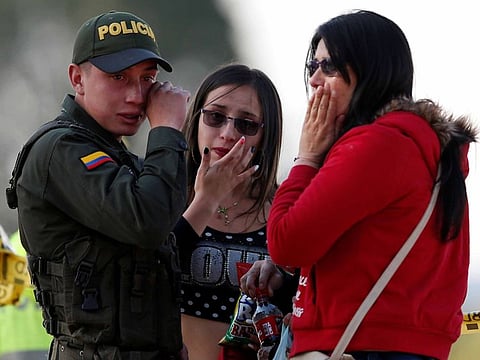 A police officer and two women wipe their tears close to the scene where a car bomb exploded, according to authorities, in Bogota, Colombia January 17, 2019
