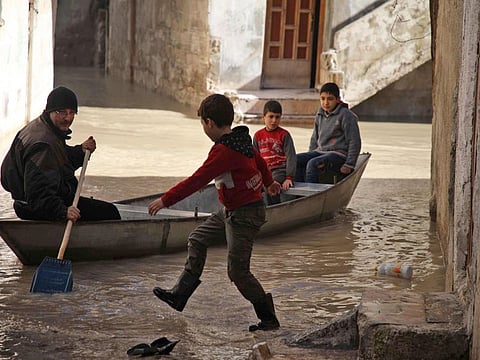 A child waits to climb into a small boat along a flooded street in the town of Darkush, in the west of Idlib province on January 17, 2019, following heavy rains that saw the Orontes River (Assi River) break its banks and flood parts of the town and the nearby orchards. 