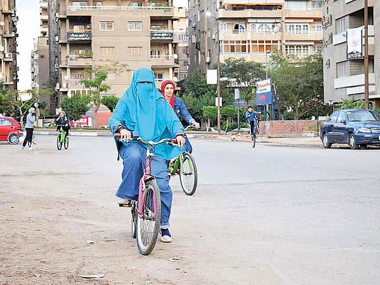 Women ride on cycles in a Cairo street.