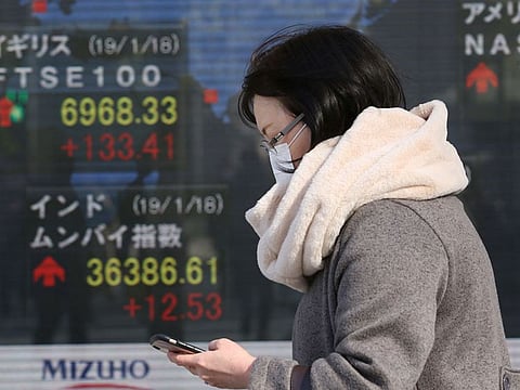 A woman walks by an electronic stock board of a securities firm in Tokyo, Monday, January 21, 2019.  