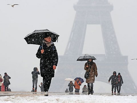 People use umbrellas against the snow as they walk on the Trocadero esplanade across from the Eiffel Tower in Paris, as winter weather hits France.