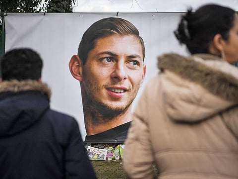 People look at a portrait of Emiliano Sala displayed in front of the entrance of the FC Nantes football club training center La Joneliere in La Chapelle-sur-Erdre on January 23, 2019, the day after the plane of Argentinian forward vanished during a flight from Nantes in western France to Cardiff in Wales. 