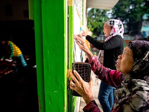 Muslim women look for their names at a voting precinct in Maguindanao
