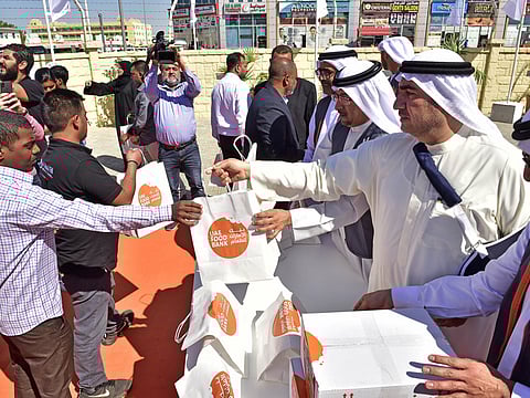 Dawood Al Hajiri and other senior Dubai Municipality officials distribute food packets provided by LuLu Group to dozens of workers in Muhaisnah 2 after launching the food bank on Tuesday.