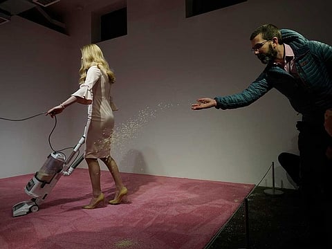 A spectator tosses crumbs for an Ivanka Trump lookalike to vacuum at Jennifer Rubell's art exhibit "Ivanka Vacuuming 2019" on Tuesday, February 5, 2019, at Flashpoint Gallery in Washington.