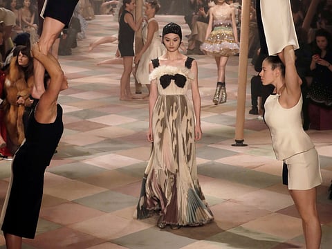 A model presents a creation by Christian Dior as acrobats perform during the 2019 Spring-Summer Haute Couture collection fashion show in Paris, on January 21, 2019.