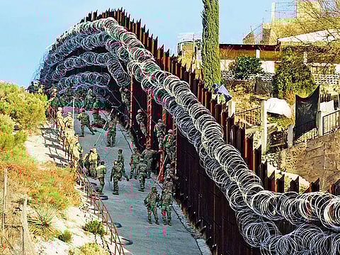 US Army troops install additional concertina wire on the border fence on a hillside above Nelson Street in downtown Nogales, Arizona. Mexico is visible at right.