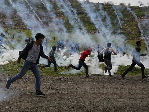 Palestinians demonstrators run away from tear gas fired by Israeli troops during a protest against Jewish colonies, in Al Mughayyir village near Ramallah, in the Israeli-occupied West Bank, on February 1, 2019.