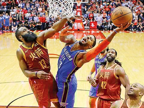 Oklahoma City Thunder forward Paul George, center, shoots as Houston Rockets guard James Harden, left, defends during the second half of an NBA basketball game in Houston.