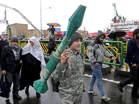 An Iranian teenager carries a mock rocket propelled grenade, during a rally marking the 40th anniversary of the 1979 Islamic Revolution, in Tehran