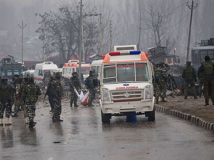 Indian paramilitary soldiers carry the remains
