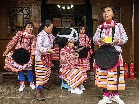 A girl (crentre) from the Long Horn Miao, a branch of the Miao ethnic minority group, getting her wig set prior to taking part in the annual flower festival or 'Tiaohuajie' in the village of Longjia in China's Guizhou province.  