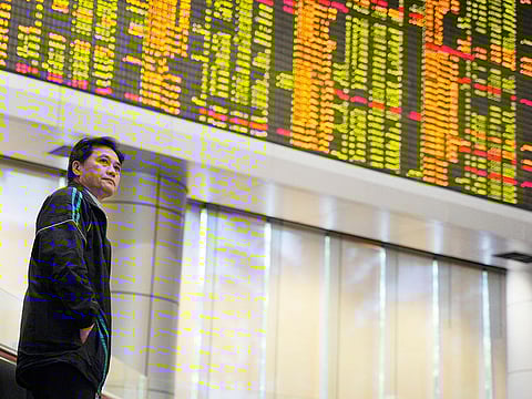 An Investor stands in front of private stock trading boards at a private stock market gallery in Kuala Lumpur, Malaysia. 