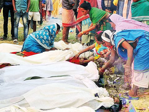 Villagers attend to the bodies of victims who died after drinking toxic liquor, at a cremation ground in Assam. 