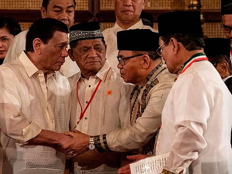 Philippine President Rodrigo Duterte (L) shakes hands with Moro Islamic Liberation Front (MILF) Chairman Murad Ebrahim during the Ceremonial Confirmation of the Bangsamoro Organic Law Plebescite Law Canvass Results and Oath-taking of Transition Authority at the Malacanang palace in Manila on February 22, 2019.   
