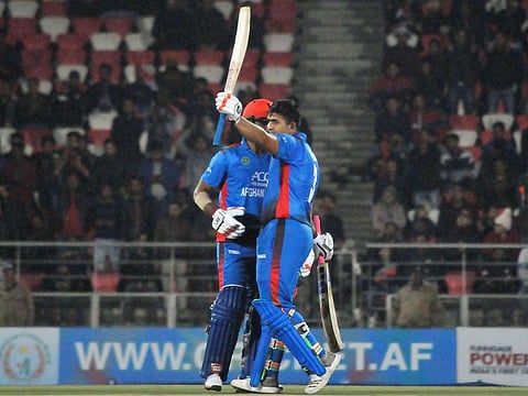 Afghan's Hazratullah Zazai raises his bat to celebrate scoring century during Afghanistan's T20 cricket match against Ireland in the northern Indian city of Dehradun on February 23, 2019. 