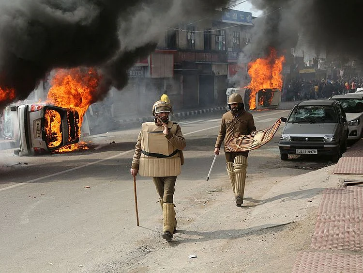 Policeman walk past vehicles set on fire