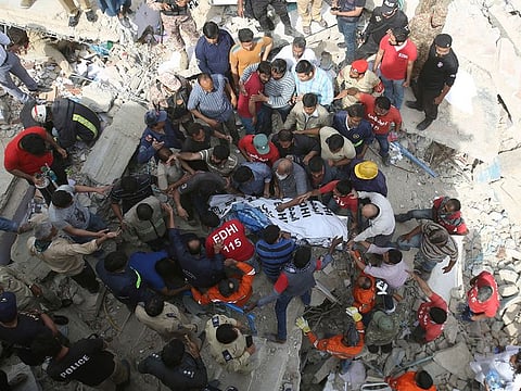 Volunteers carry a body of a victim from a collapsed building in Karachi, Pakistan, Monday, Feb. 25, 2019. The small residential building collapsed as construction work was underway next to it in the city's Malir neighborhood.