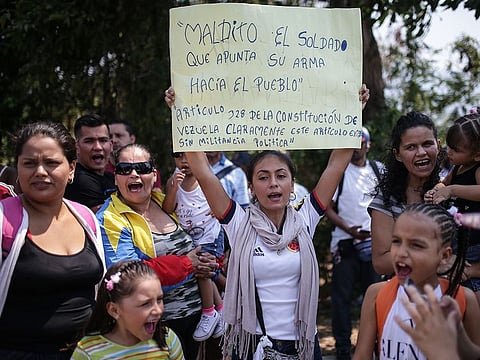 Demonstrators hold signs and shout slogans during a protest against Nicolas Maduro, Venezuela's president, at the entrance of the Tienditas International Bridge in Cucuta, Colombia.