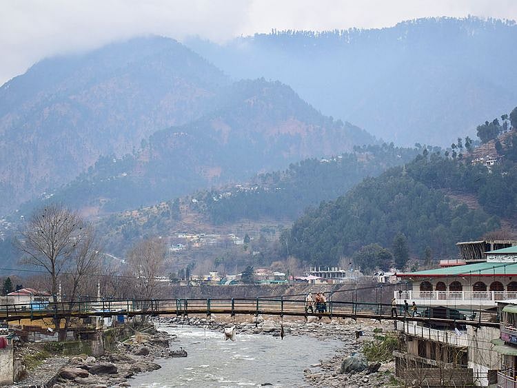 Pakistani residents walk on a bridge