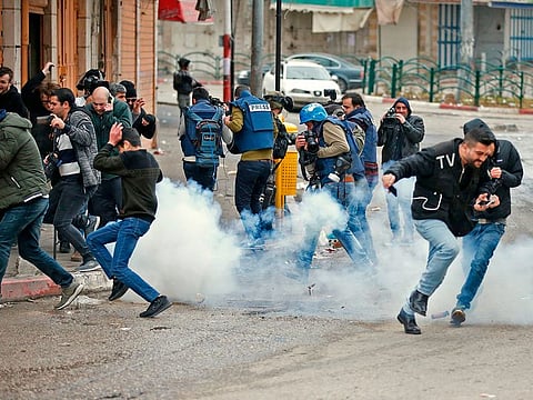 Israeli soldiers throw sound grenades at a group of people including journalists, near a gate leading to Hebron's main al-Shuhada street, closed by troops earlier in February, during an annual demonstration in memory of the 1994 Ibrahimi Mosque massacre, in the divided West Bank city of Hebron, on February 22, 2019.