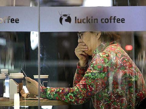 The logo is seen next to a customer at a Luckin Coffee store in Beijing, China, February 28, 2019. 