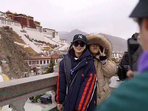 Tourists pose for souvenir photos in front of the Potala Palace in Lhasa, southwest China's Tibet Autonomous Region.