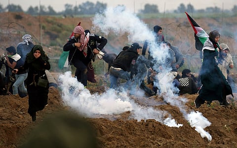 Palestinian demonstrators run away from teas gas fired by Israeli forcers during a protest at the Israel-Gaza border fence, in the southern Gaza Strip on March 1, 2019.