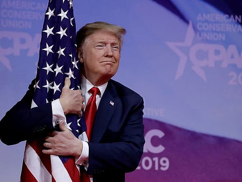 U.S. President Donald Trump hugs American flag at the Conservative Political Action Conference (CPAC) annual meeting at National Harbor near Washington, U.S., March 2, 2019.