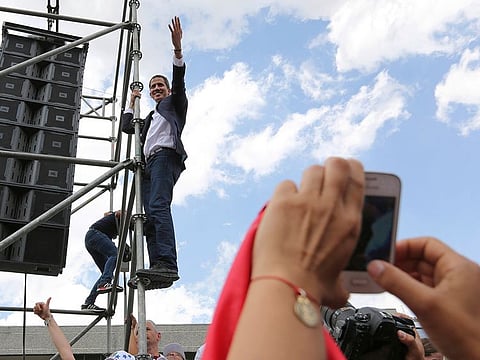 Venezuelan Congress President Juan Guaido, an opposition leader who declared himself interim president, waves from the scaffolding after speaking at a rally demanding the resignation of Venezuelan President Nicolas Maduro in Caracas, Venezuela, Monday, March 4, 2019.