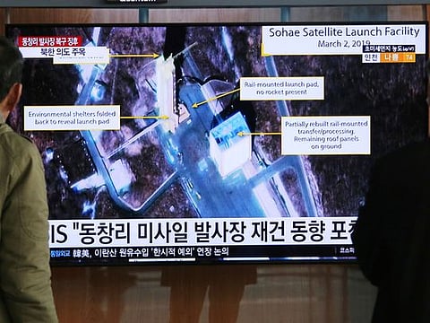 People watch a TV screen showing an image of the Sohae Satellite Launching Station in Tongchang-ri, North Korea, during a news program at the Seoul Railway Station in Seoul, South Korea, Wednesday, March 6, 2019. North Korea is restoring facilities at a long-range rocket launch site that it dismantled last year as part of disarmament steps, according to foreign experts and a South Korean lawmaker who was briefed by Seoul's spy service. The signs read: " North's Tongchang-ri launch site." 
