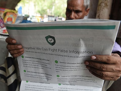 In this file photo illustration taken on July 10, 2018 shows an Indian newspaper vendor reading a newspaper with a full back page advertisement from WhatsApp intended to counter fake information, in New Delhi. A deluge of online hoaxes that hit Indian social media as the country fought aerial battles with neighbouring Pakistan has heightened fears over the "fake news" war looming in India's national election.