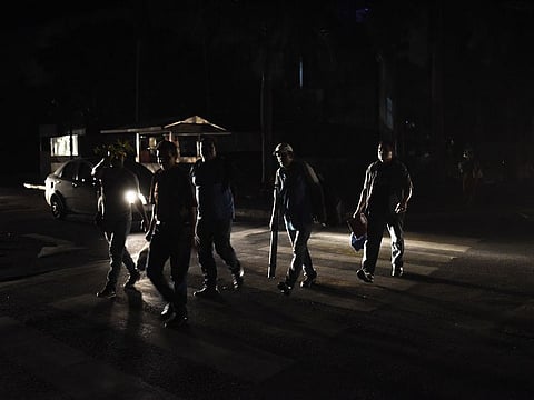 Residents lit by the lights of vehicles walk during a major blackout in the Los Palos Grandes neighborhood of Caracas, Venezuela.