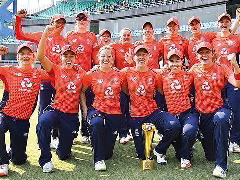 England’s players with the winning trophy pose for a photograph after winning the final match of the women's Twenty20 (T20) cricket series between India and England at the Barsapara Cricket Stadium in Guwahati