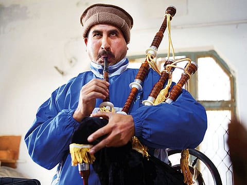 A Pakistani worker plays and tests a set of bagpipes at the Mid East bagpipe factory.