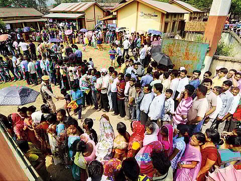 Voters wait in queues to cast votes at a polling station at Bonda during assembly elections in Kamrup district of Assam