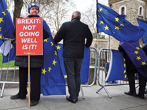 An anti-Brexit campaigner holds a placard as EU flags flutter during a protest near the Houses of Parliament in London on March 13, 2019. 
