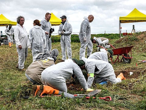Forensic workers and experts inspect a zone during the exhumation of a mass-grave of hundreds of Yazidis killed by Daesh militants.